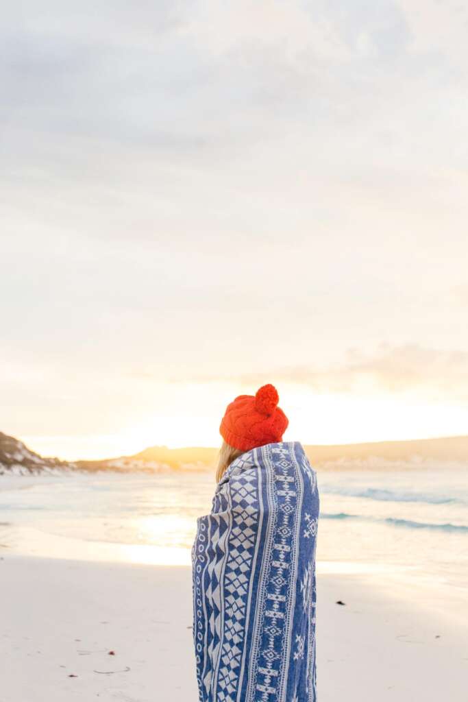 Woman wrapped in blanket on beach,