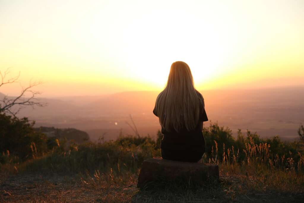 Woman sitting watching sunset. 